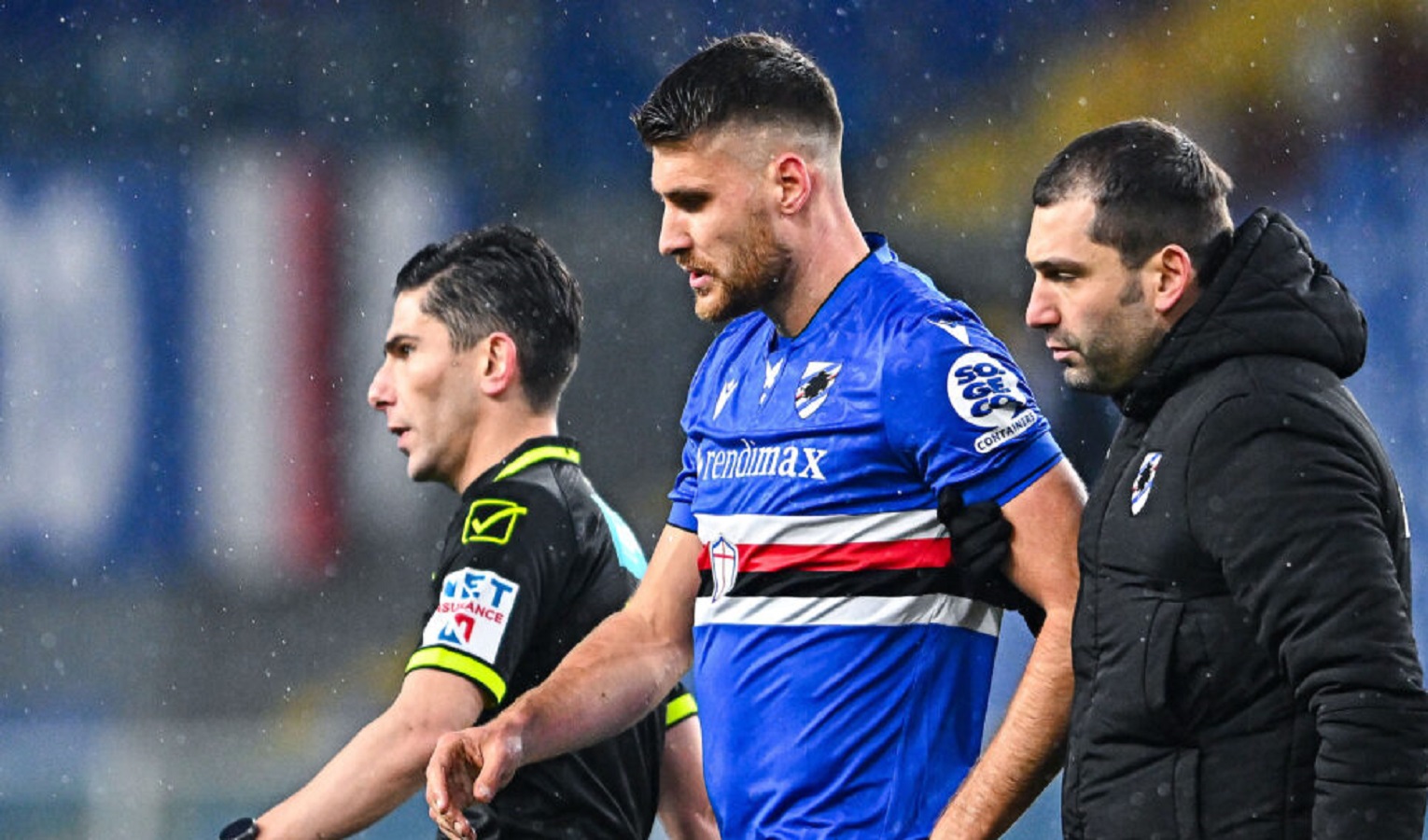 Un arbitro, un calciatore della Sampdoria e un uomo vestito con una tuta