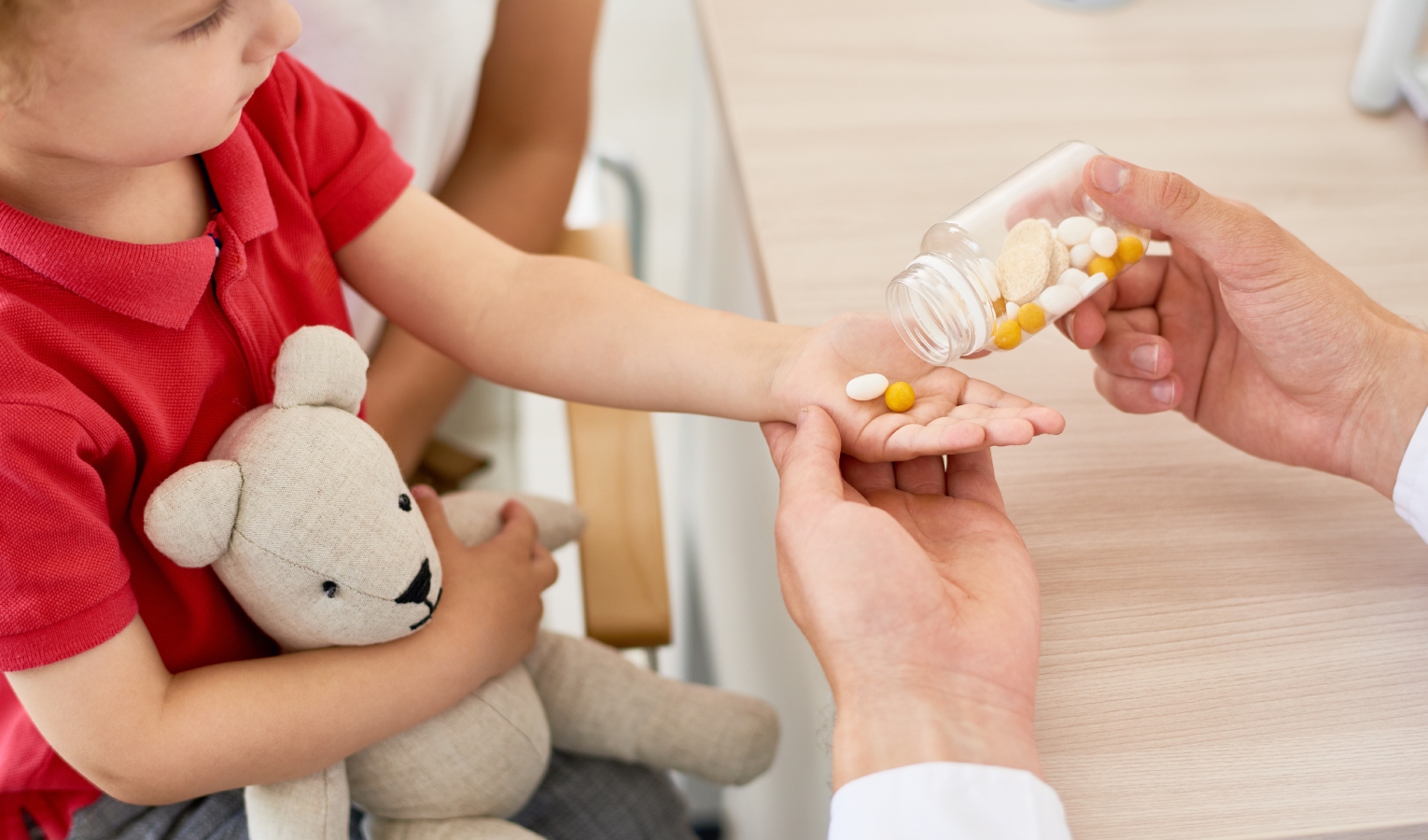 Bambino con peluche e pastiglie in mano