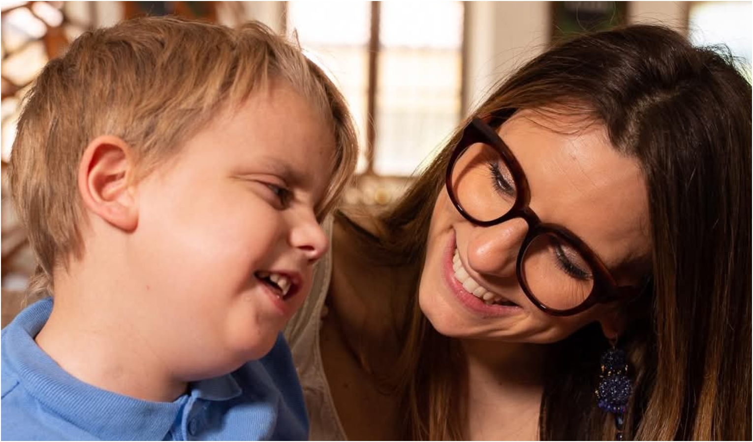 Bambino biondo sorridente con donna con occhiali e capelli lunghi