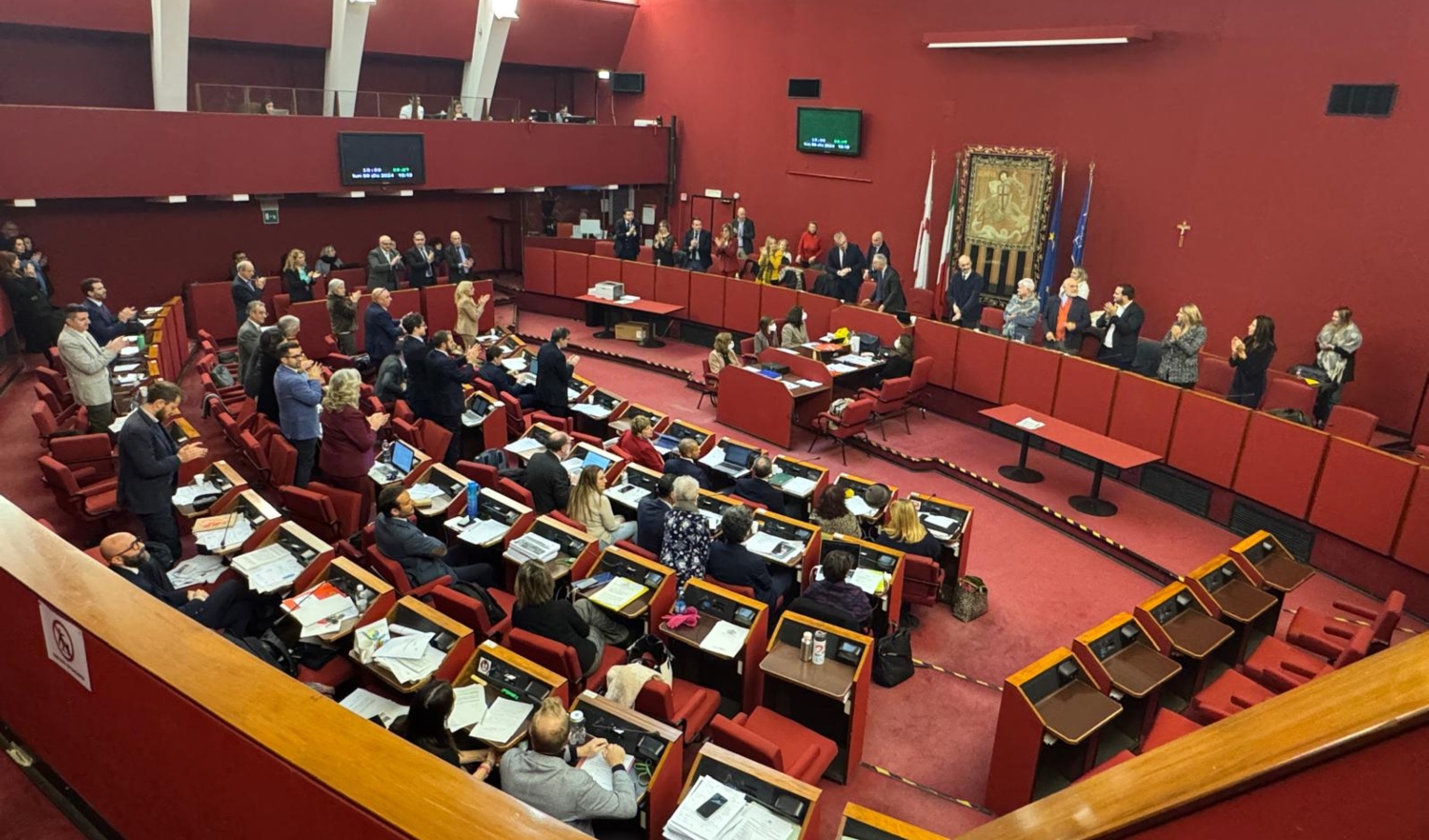 Persone sedute e in piedi in un'aula tappezzata di rosso