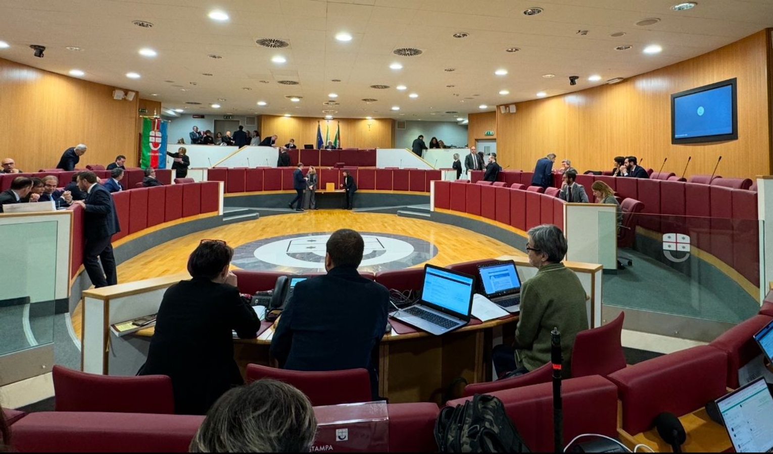 Un'aula con poltrone rosse e persone sedute e in piedi