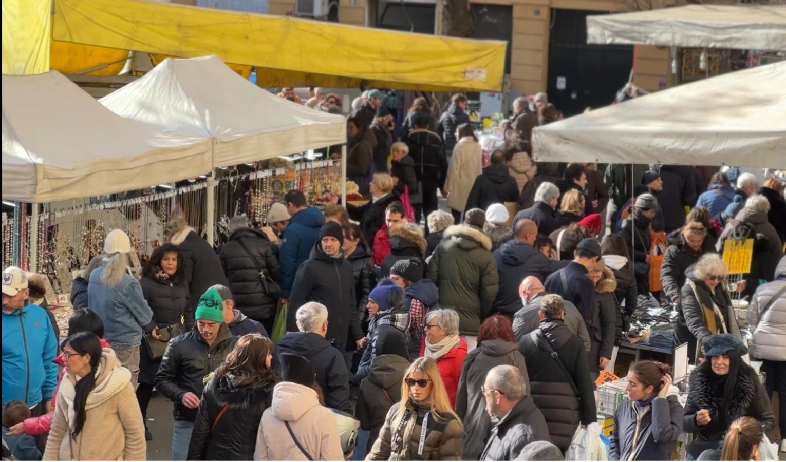 Gente che cammina in mezzo ai banchi di una fiera