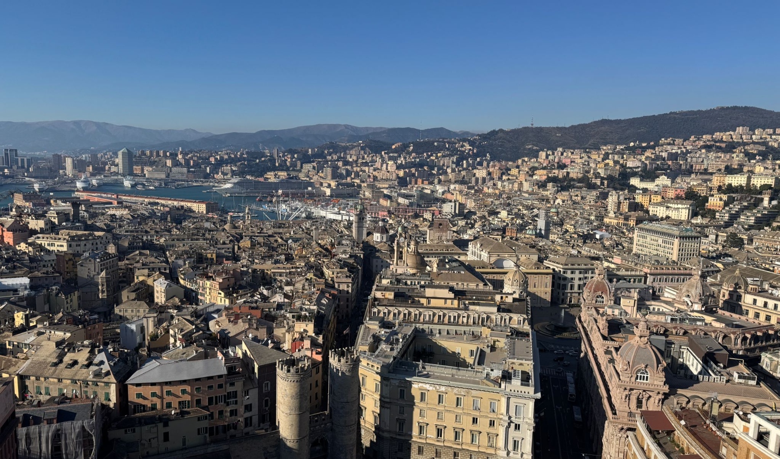 Un insieme di palazzi con lo sfondo sul mare e il cielo azzurro della città di Genova