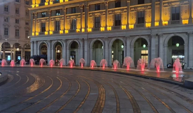 Una piazza di una città illuminata con fontane colorate