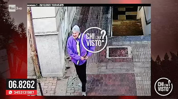 Un uomo con giacca a vento viola e cappello grigio