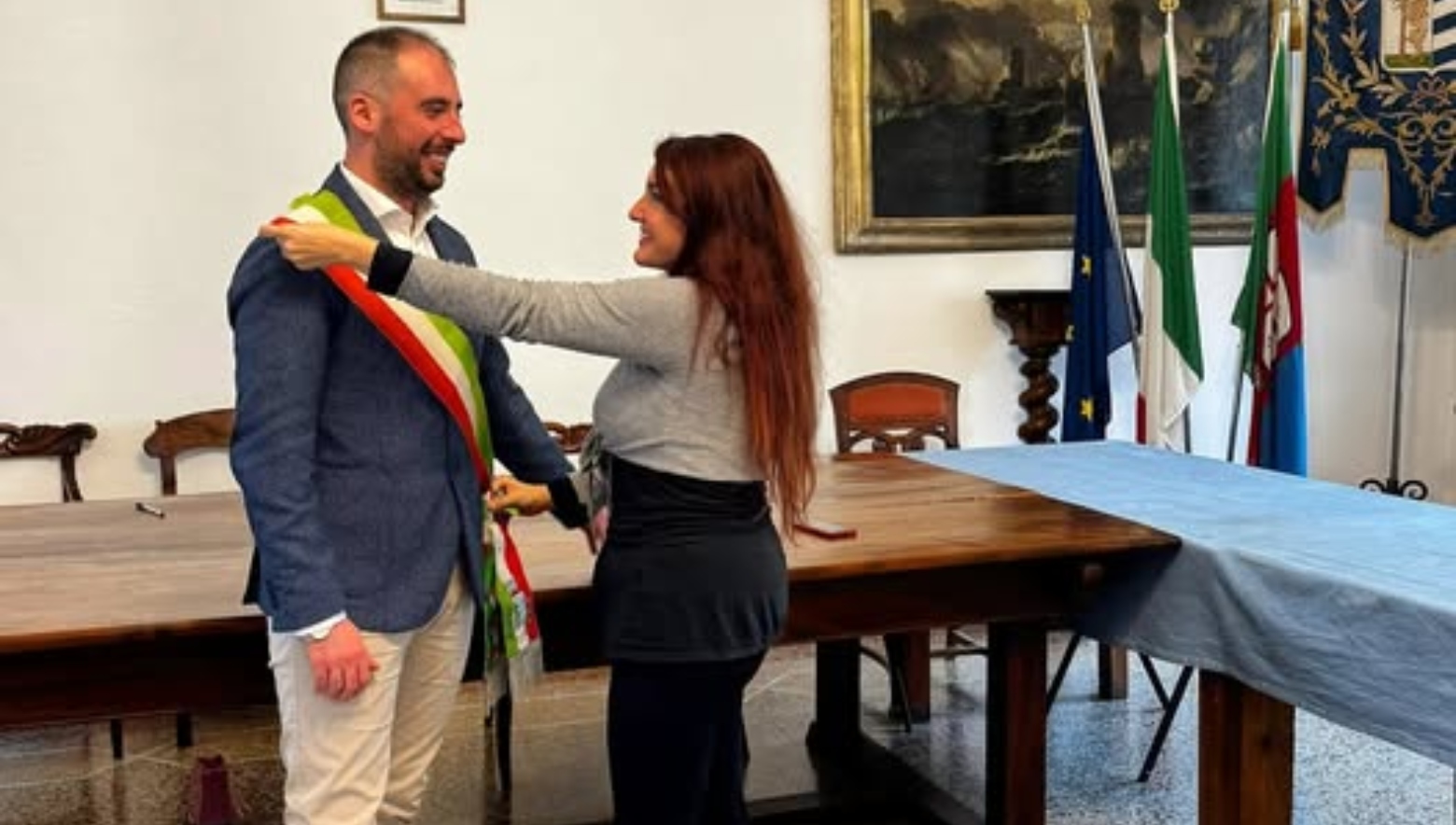 Una donna veste un uomo della fascia tricolore