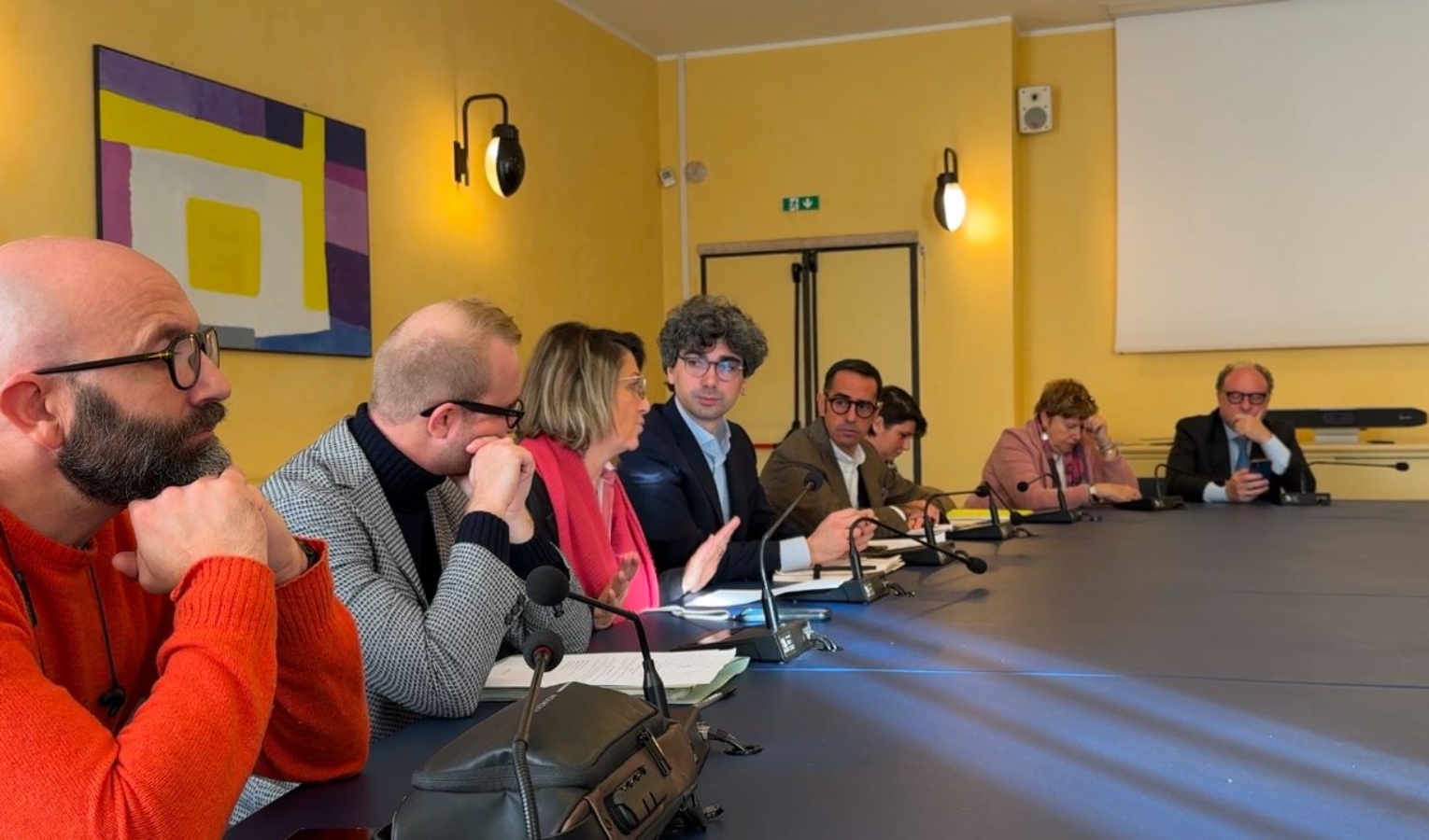 Diverse persone sedute a un tavolo tengono una conferenza stampa