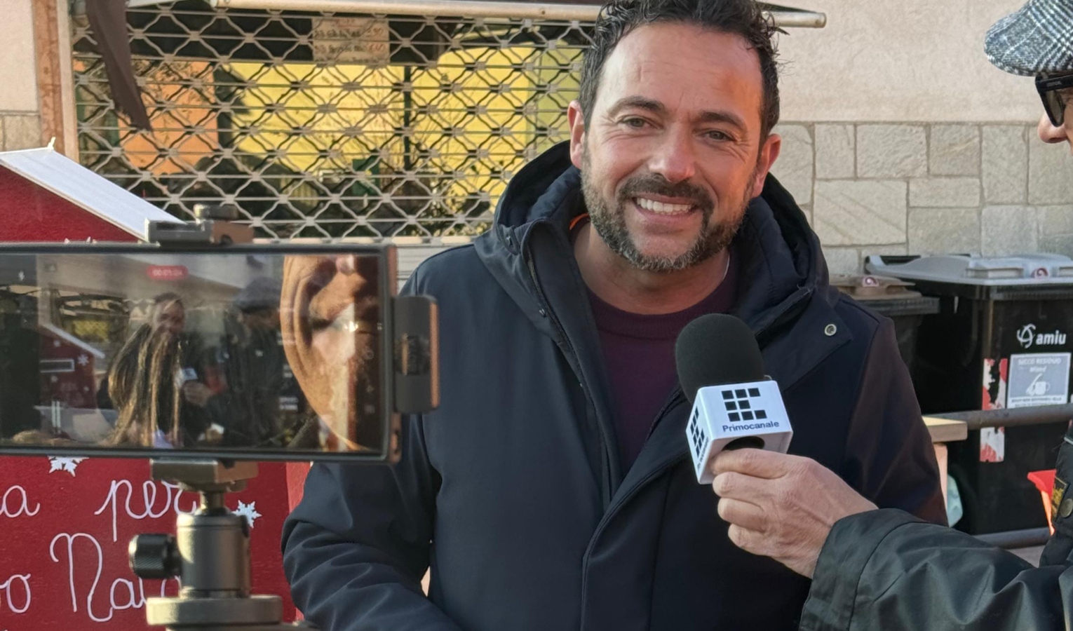 Un uomo in giacca intervistato da una televisione